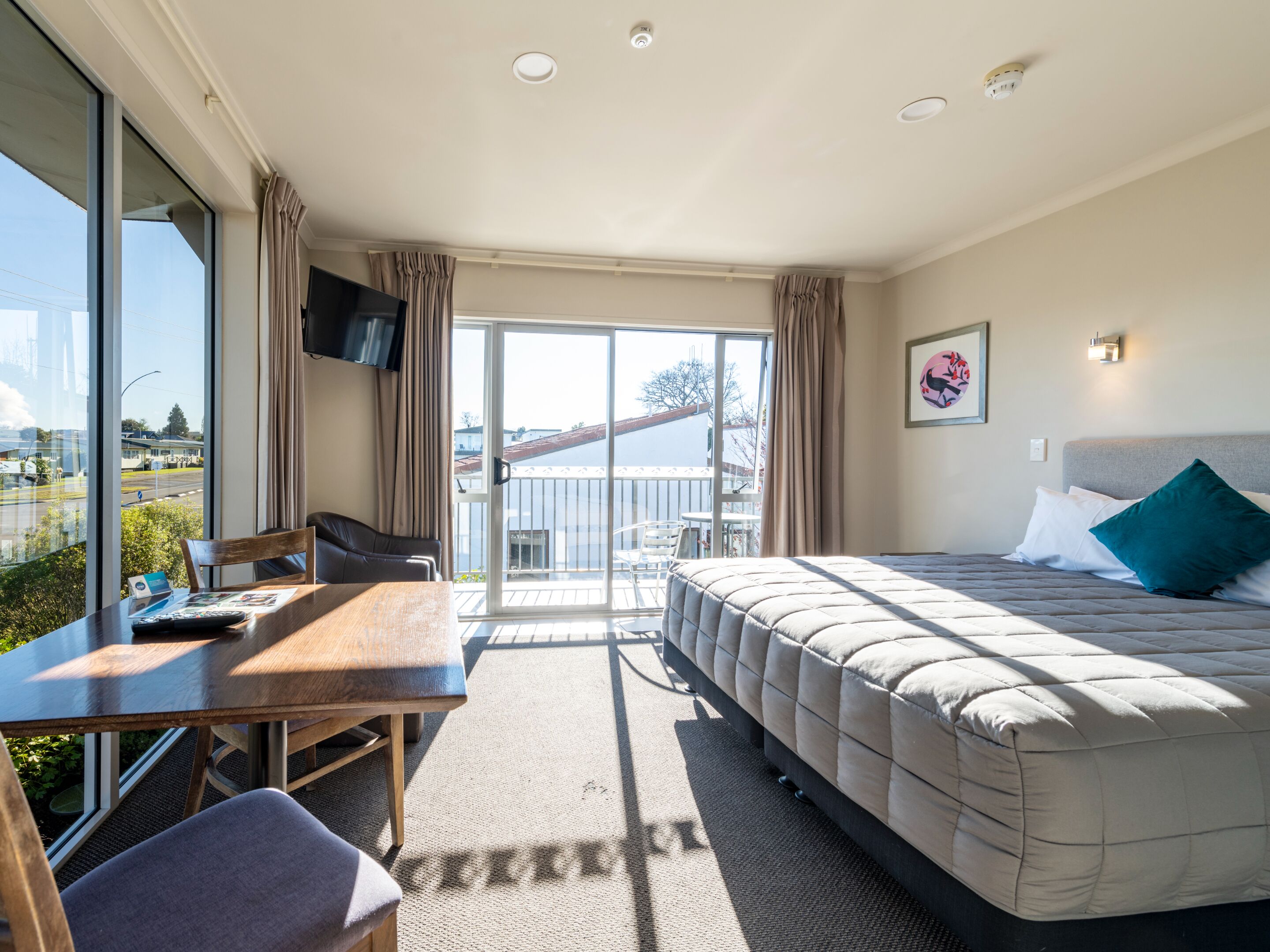 Ein Hotelzimmer mit Bett, Schreibtisch, Stuhl und einem großen Fenster.