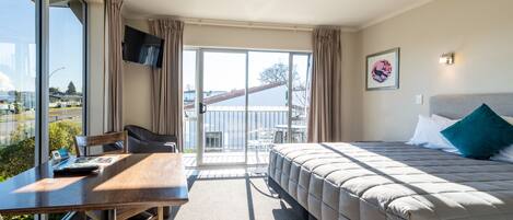 A hotel room with a bed, a desk, a chair, and a large window.