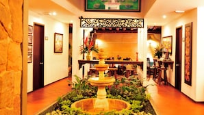 A hotel lobby with a central fountain, a reception desk, and a dining area. - San Antonio Hotel Boutique (Cali)