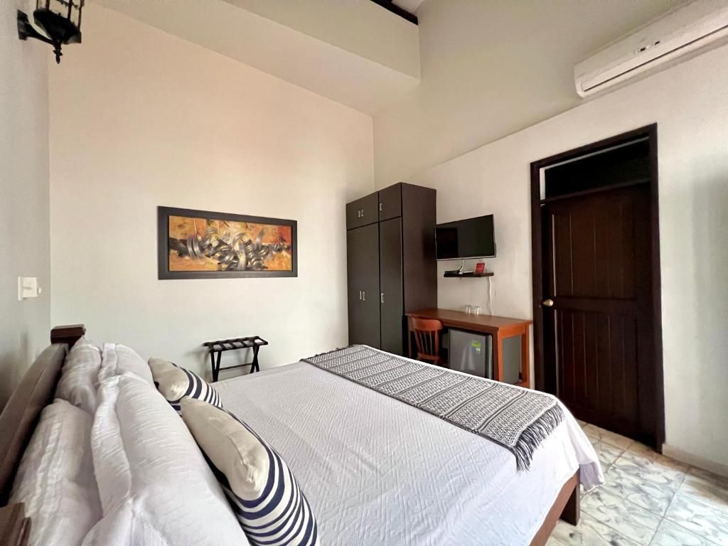 Une chambre d’hôtel avec un lit, un bureau, une télévision et une porte.