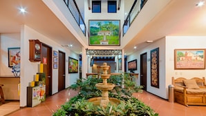 A spacious lobby with a central fountain, artwork on the walls, and a comfortable seating area. - San Antonio Hotel Boutique (Cali)