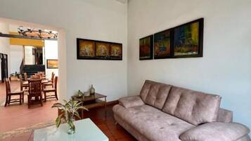 A living room with a sofa, a coffee table, and a dining area with chairs and a table.