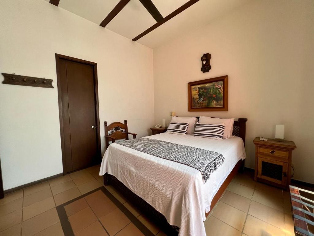 Un dormitorio con cama, mesita de noche, puerta de madera y un reloj en la pared.
