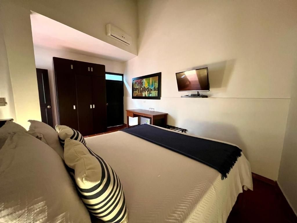 Hotellihuone, jossa on sänky, työpöytä, televisio ja ovi.