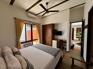 Ein Schlafzimmer mit einem Bett, einem Schreibtisch, einem Fernseher und einem Deckenventilator.