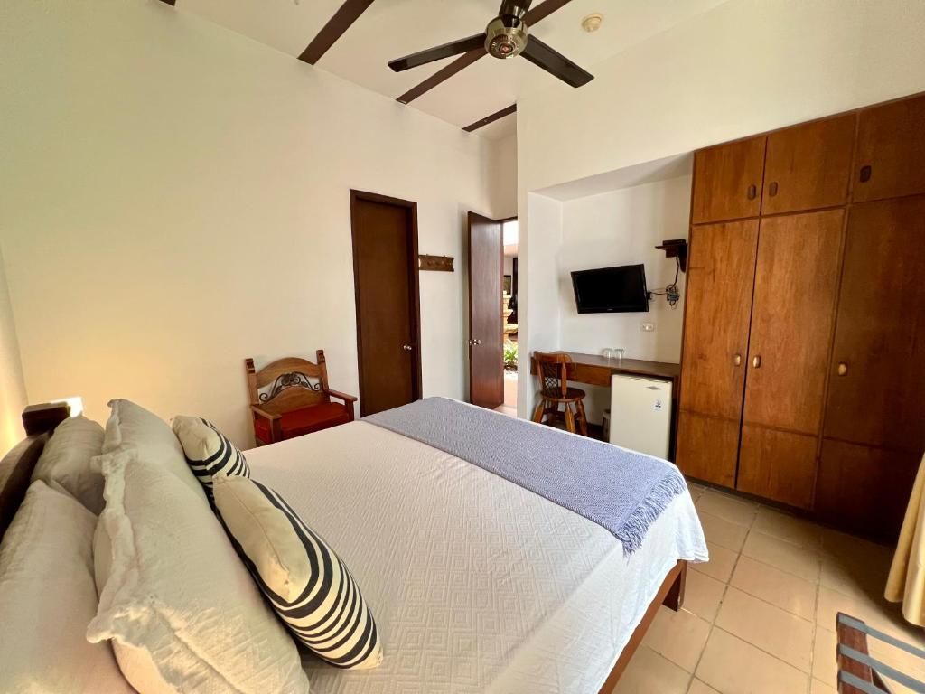 Ein Schlafzimmer mit Bett, Kissen, Schreibtisch, Fernseher und Kleiderschrank.