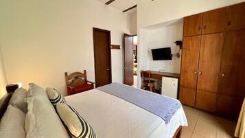 Ein Schlafzimmer mit Bett, Kissen, Schreibtisch, Fernseher und Kleiderschrank.