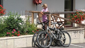 A child standing next to a wooden fence with bicycles parked nearby. - Apartments Bohinj na vasi (Bohinj)