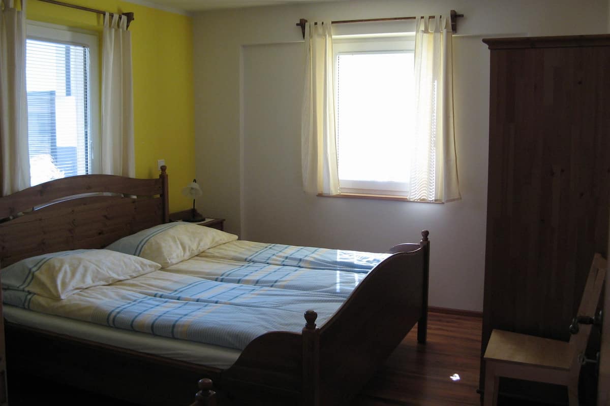 Une chambre à coucher avec un lit simple, une table de chevet, une lampe et une armoire en bois.