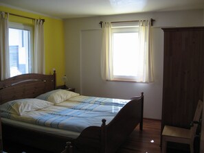 Une chambre à coucher avec un lit simple, une table de chevet, une lampe et une armoire en bois.