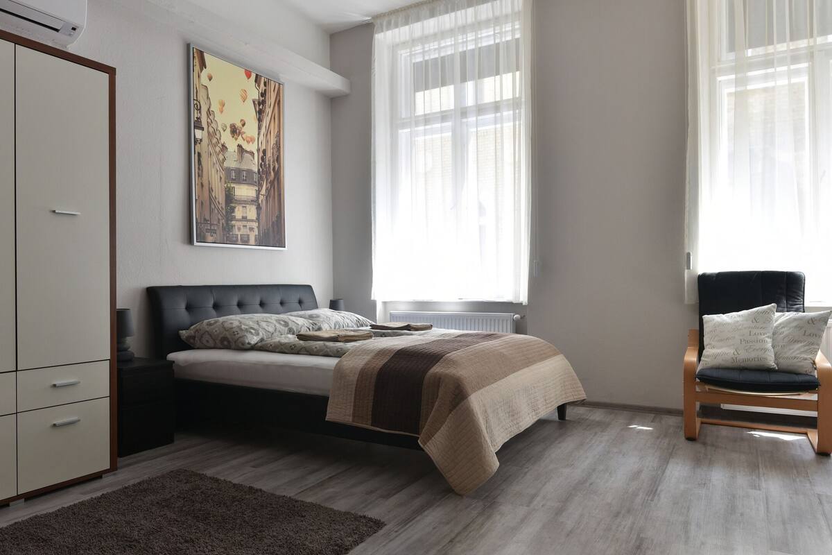 A bedroom with a bed, a wardrobe, a chair, and a window.