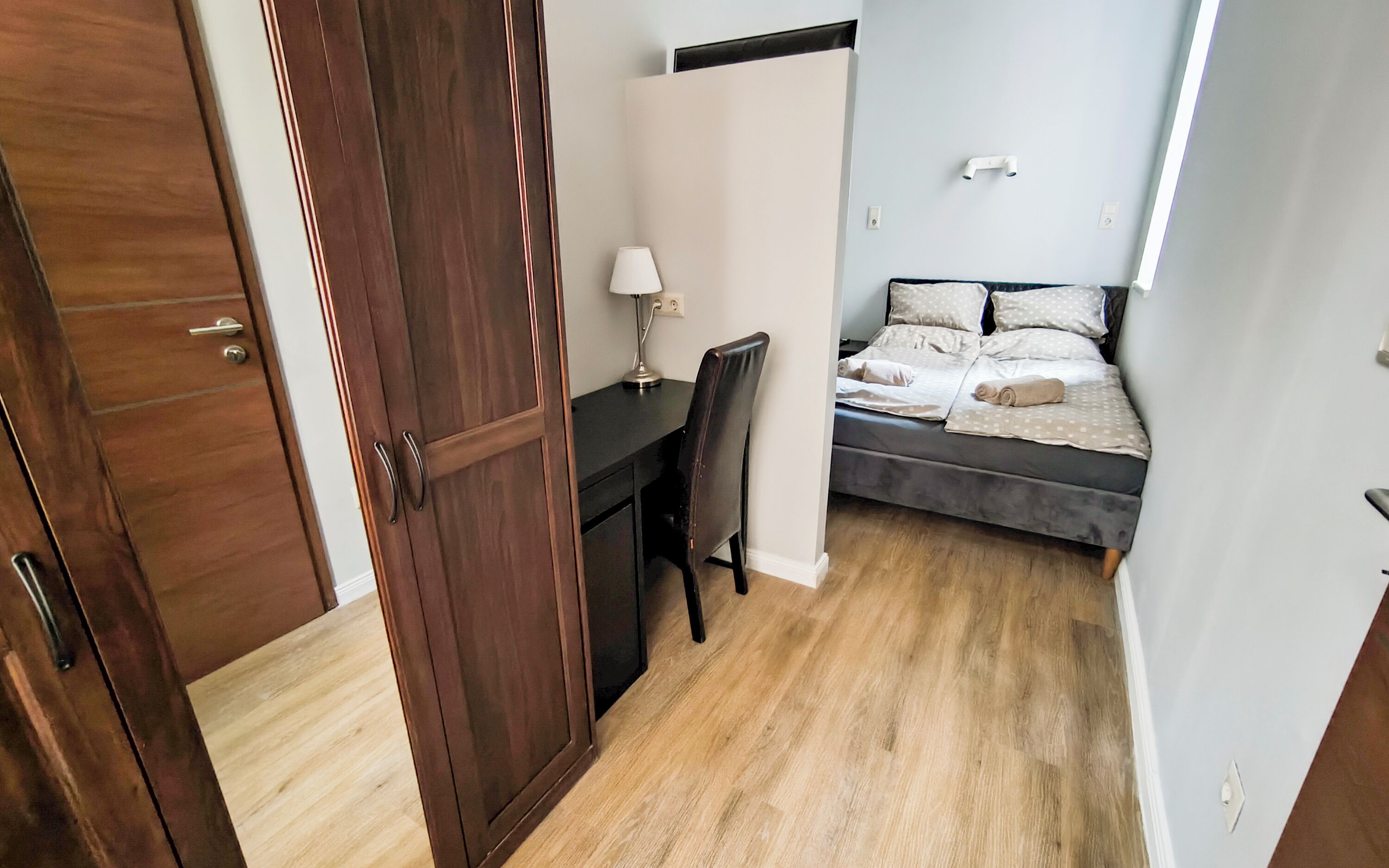 A bedroom with a bed, a desk, and a chair.