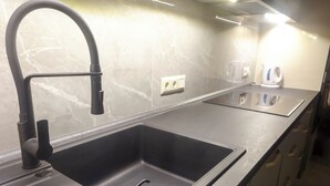 A modern kitchen with a sleek black faucet, a built-in soap dispenser, and a marble backsplash. - Corvin Point Rooms and Apartments (Budapest)