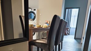 A hallway with a dining area, a washing machine, and a window with curtains. - Corvin Point Rooms and Apartments (Budapest)