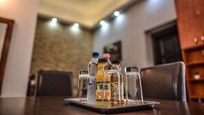 A dining table with a tray holding various beverages and a glass. The room has a stone wall and a wooden cabinet in the background. - Corvin Point Rooms and Apartments (Budapest)