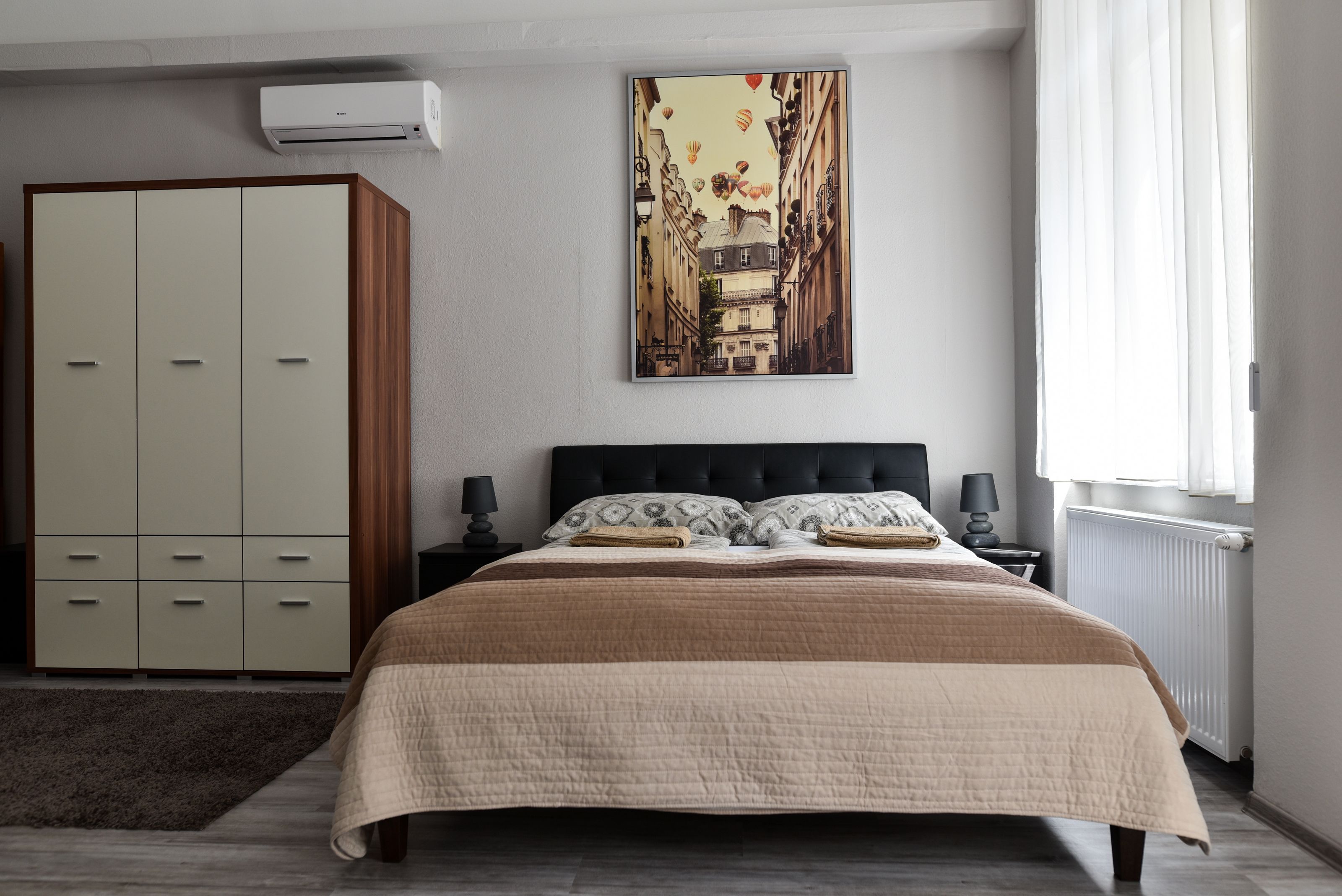 A bedroom with a bed, a wardrobe, a radiator, and a wall-mounted air conditioner.