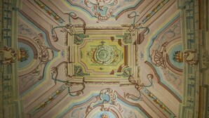 Een gedetailleerd plafond met decoratieve versieringen en een centraal medaillon.