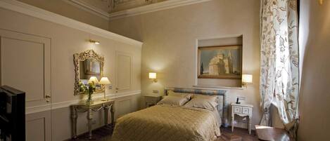 A hotel room with a bed, a nightstand, a mirror, a painting, and a curtain.
