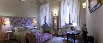 Un dormitorio con cama, sofá, una mesita redonda, una silla y un espejo.