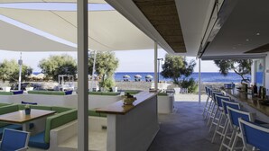 An outdoor seating area with a view of the beach and ocean. - Glykeria Mini Suites (Santorini)
