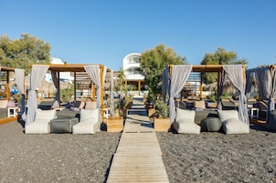 Playa privada, arena negra, sillas reclinables de playa, sombrillas