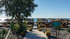 A wooden deck leading to beach chairs and umbrellas, with a clear view of the sea. - Glykeria Mini Suites (Santorini)