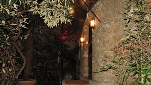 A stone staircase leading to a door with a red mat, surrounded by lush greenery and a stone wall. - Hôtel Windsor Home (Paris)