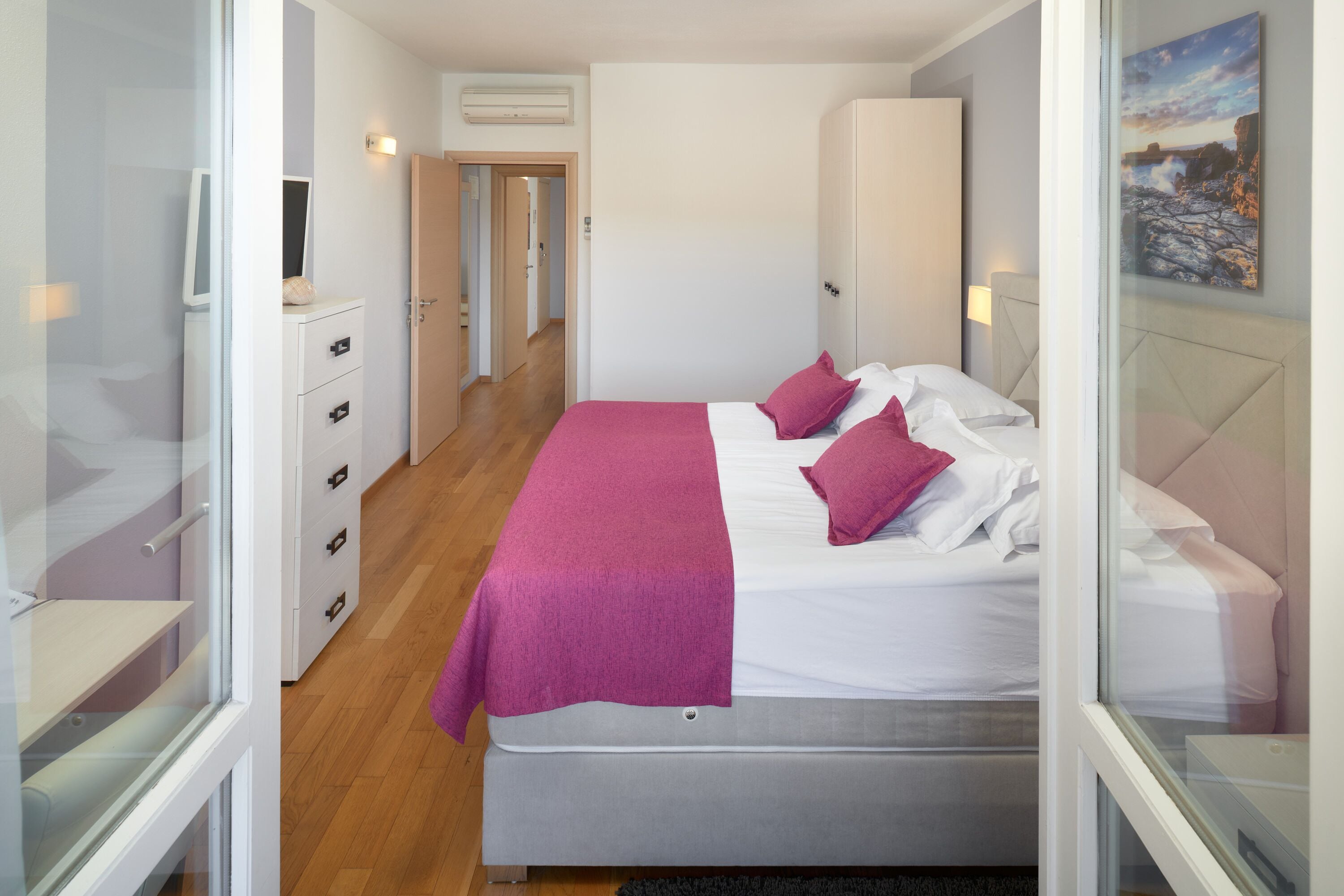 A bedroom with a bed, a wardrobe, a desk, and a window.