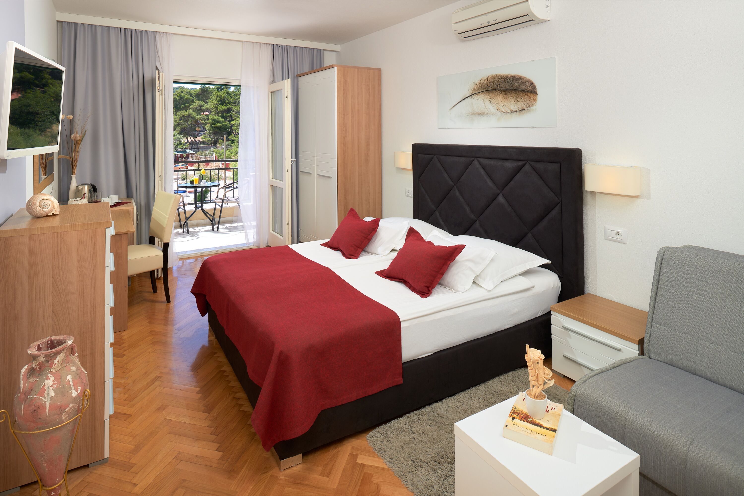 Ein Hotelzimmer mit Bett, Schreibtisch, Sessel, einer Couch und Blick ins Freie.