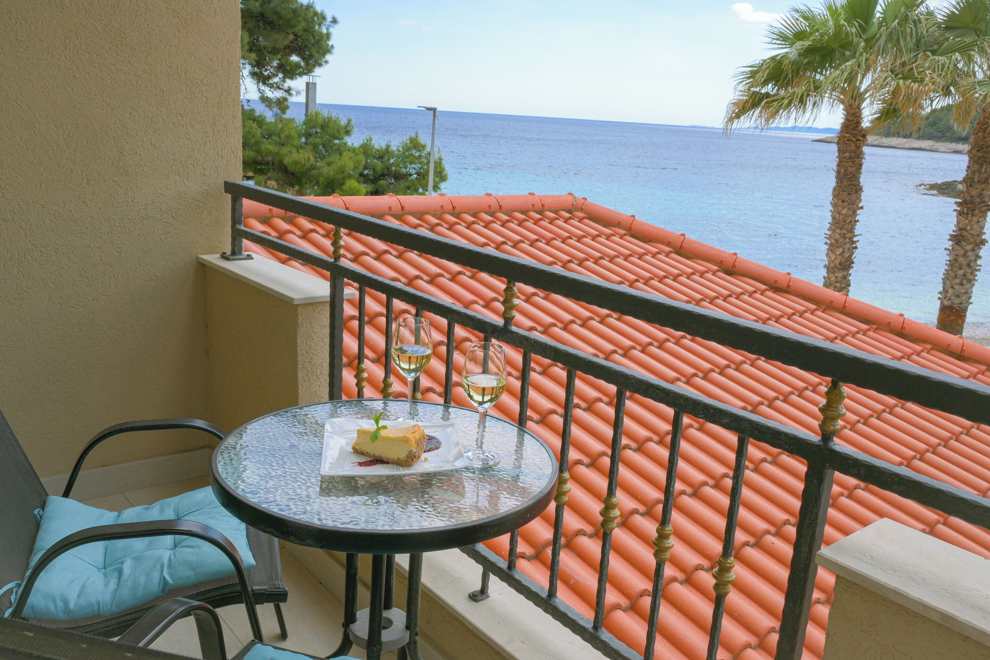 A balcony with a table, chairs, and a view of the sea.