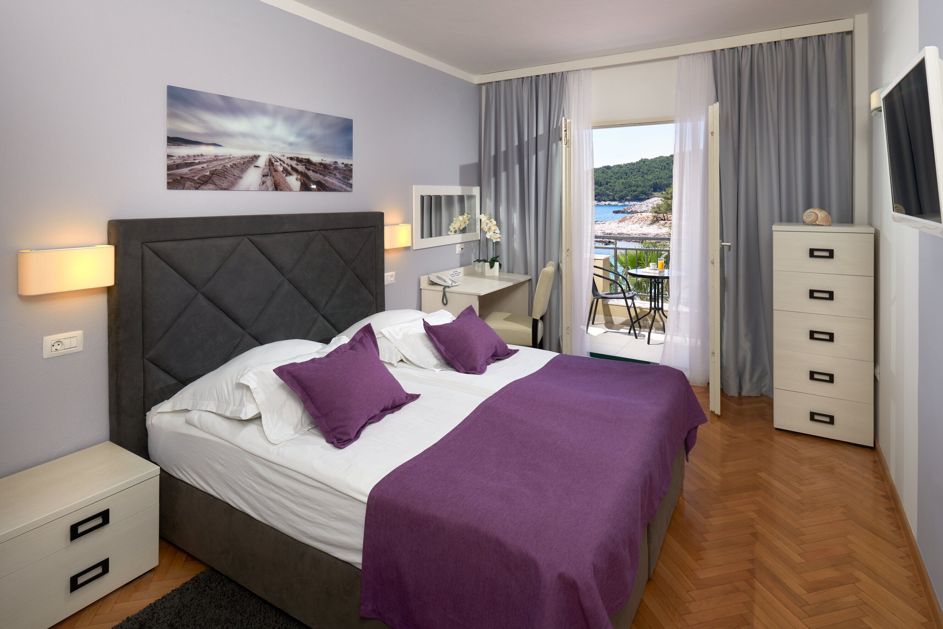 A neatly arranged bedroom with a bed, bedside table, and a desk with a chair.