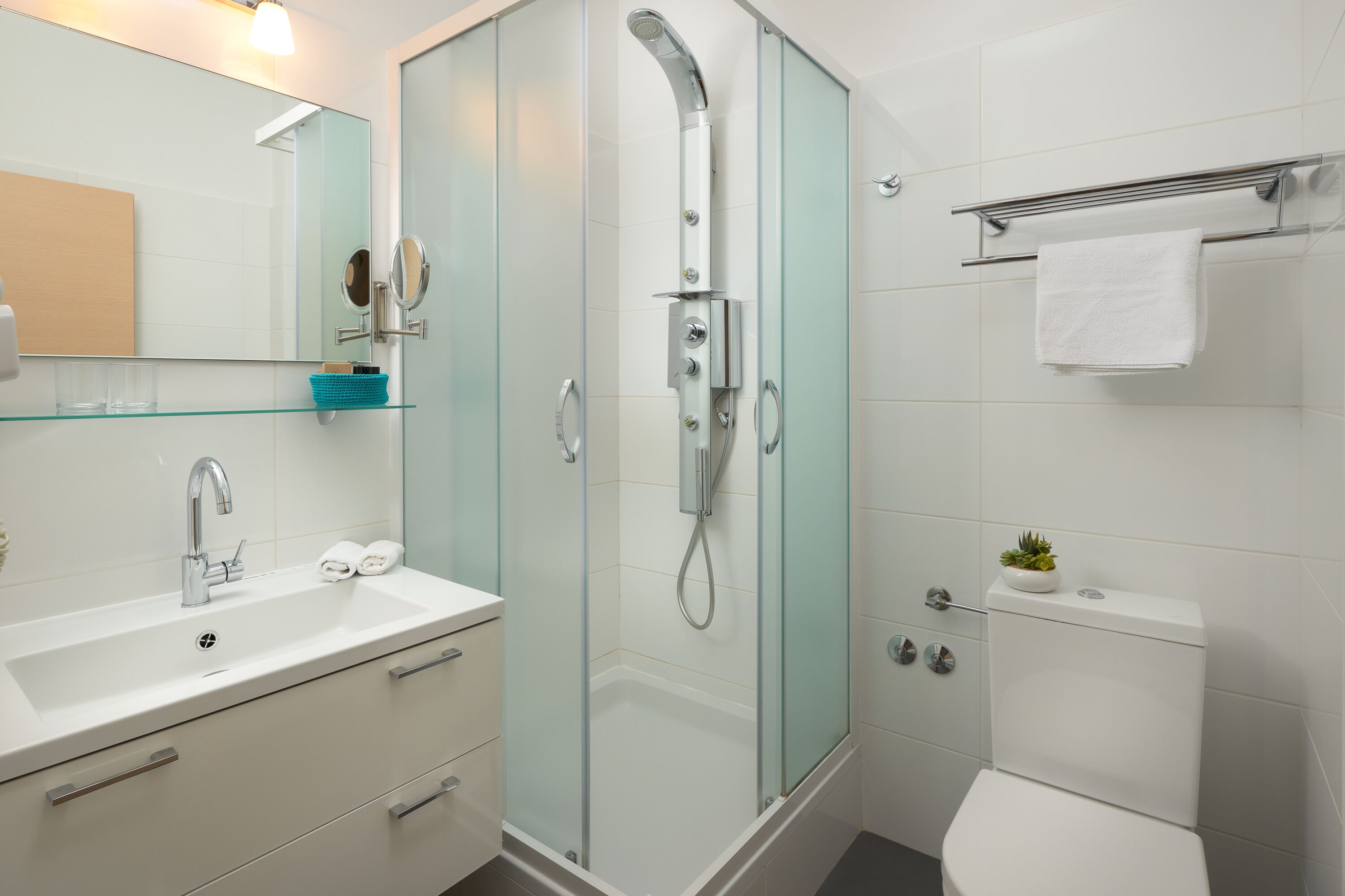 Ein modernes Badezimmer mit einer Duschkabine, einem weißen Waschbecken und einer Toilette.