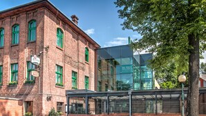 Ein Hotel mit Ziegelaußenwand, grünen Fenstern und einem modernen Glasanbau.