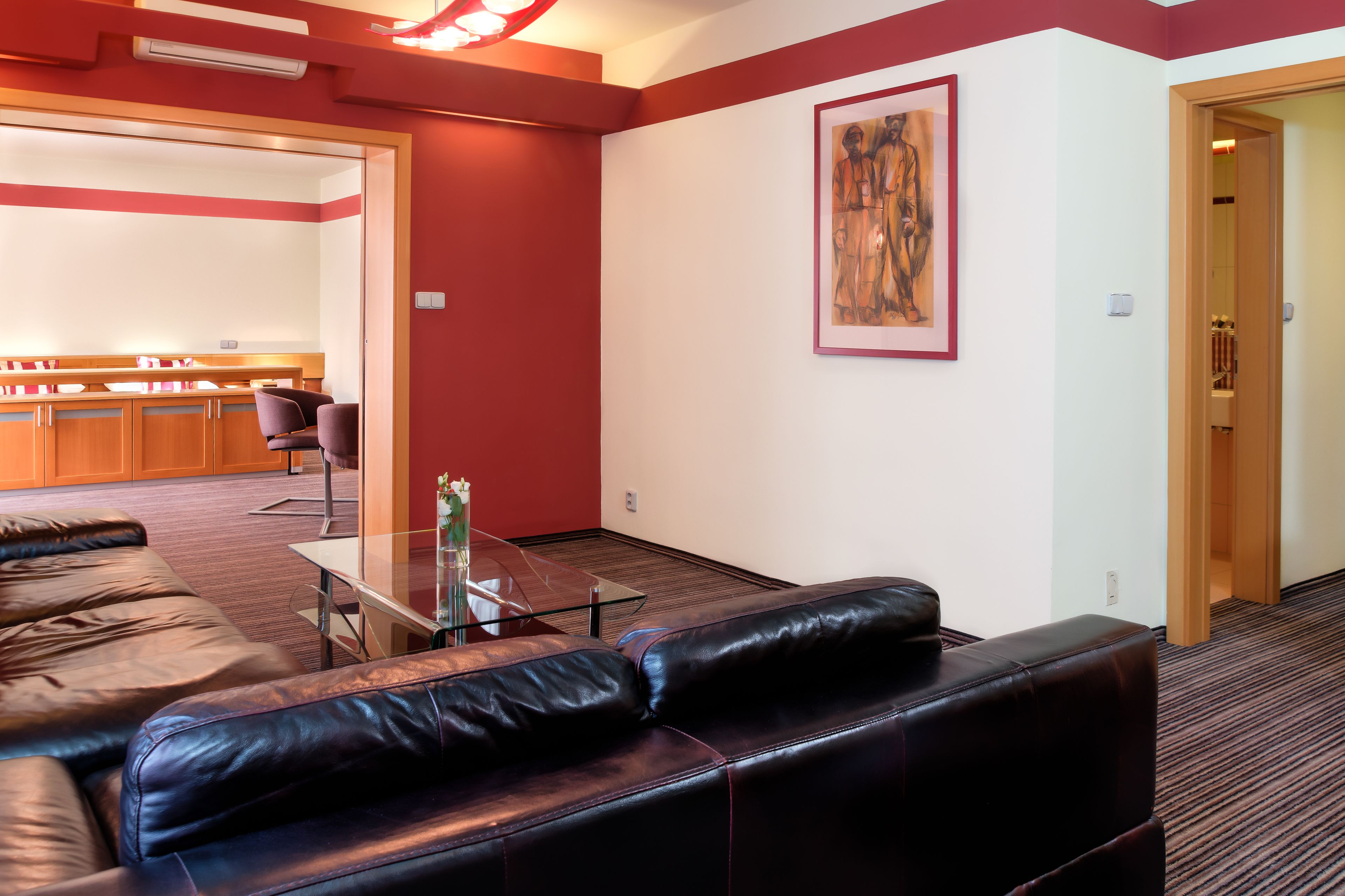 Ein modernes Wohnzimmer mit einer Ledersofa, einem Glastisch und einer roten Akzentwand.