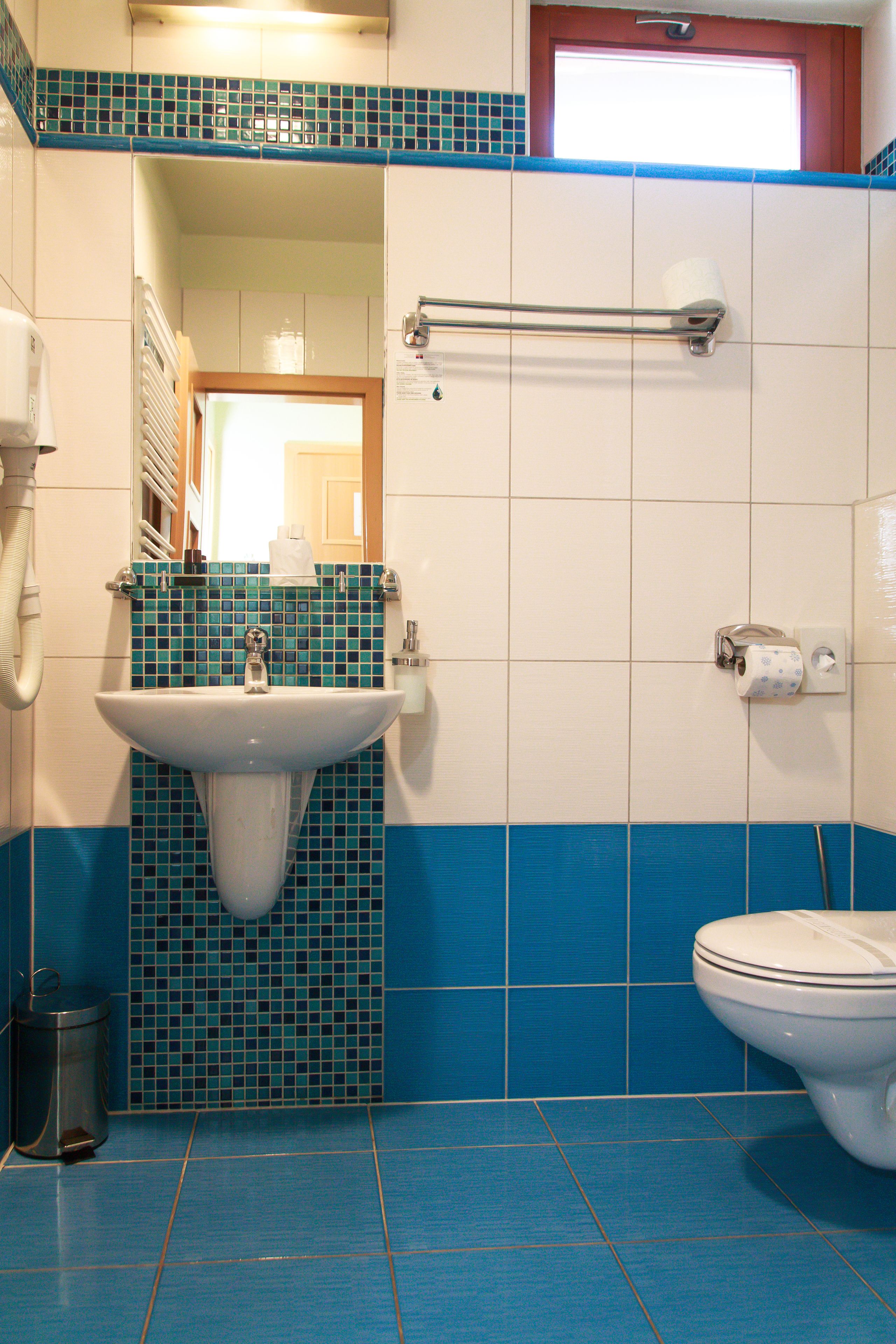Een badkamer met een wastafel, toilet en wandtegels in blauw.