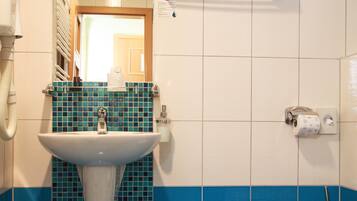 Een badkamer met een wastafel, toilet en wandtegels in blauw.