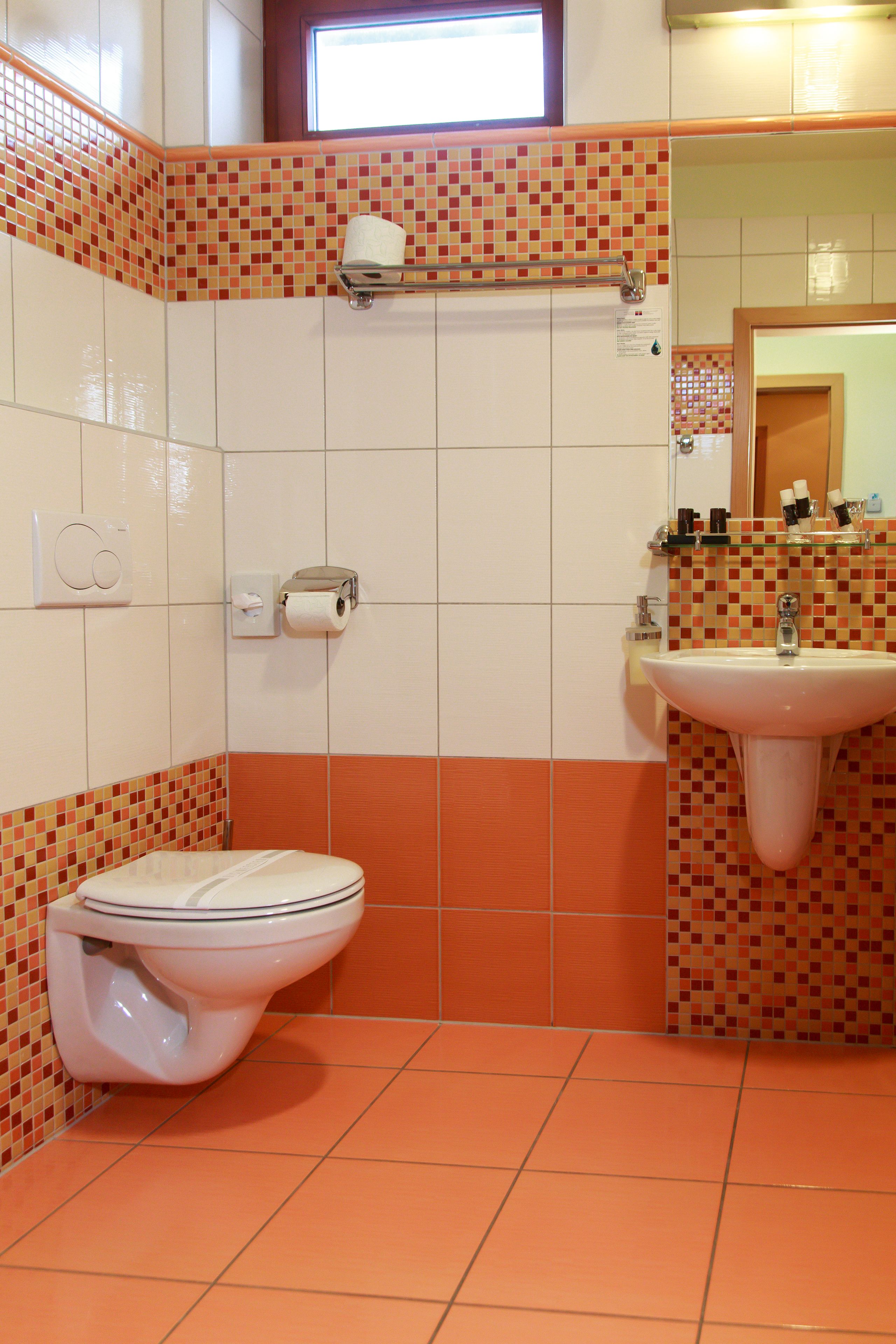 A bathroom with a toilet, sink, and tiled walls.
