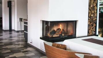 Un interior moderno con chimenea, sillas de madera y un suelo estampado.