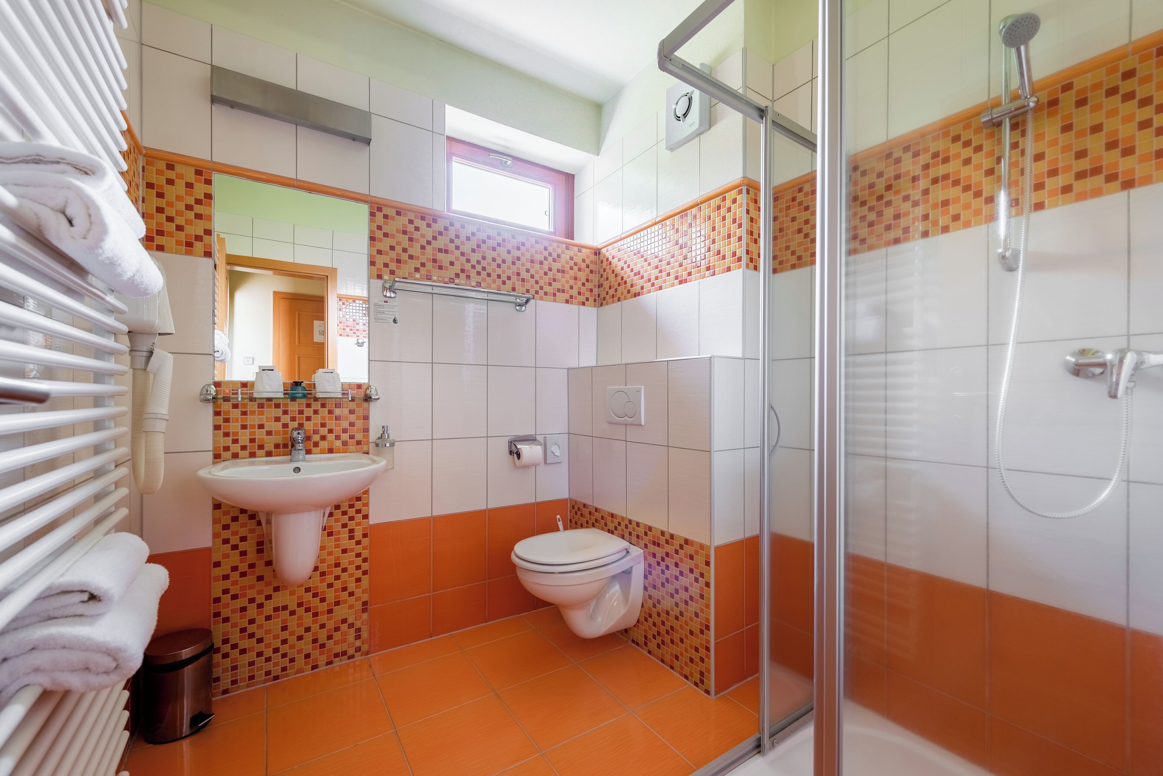A bathroom with a glass shower enclosure, a sink, and a toilet.