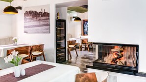 Ein modernes Hotelzimmer mit Kamin, Essbereich und einem großen Fenster mit Blick auf die Stadt.