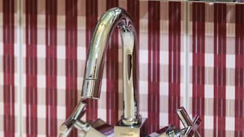A bathroom with a modern faucet and multiple bottles of hand soap on a shelf.