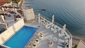 A rooftop pool area with lounge chairs and a view of the sea. - Hotel Belveder (Pag)