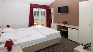 A hotel room with a bed, desk, chair, and a TV mounted on the wall. - Hotel Belveder (Pag)