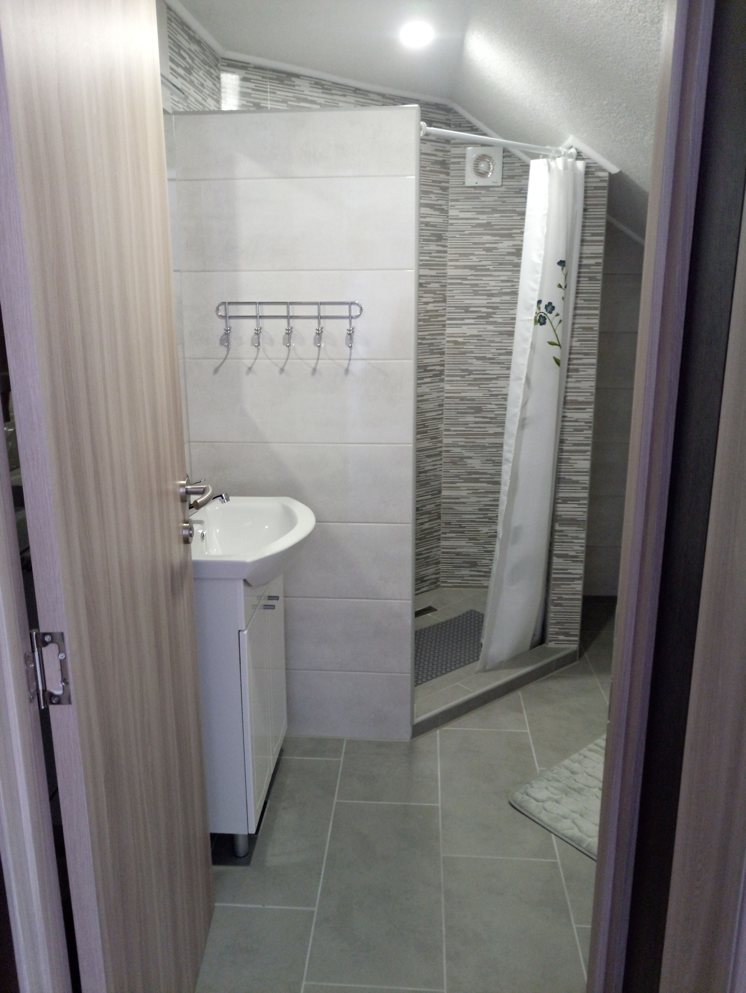 A bathroom with a shower, a sink, and a towel rack.