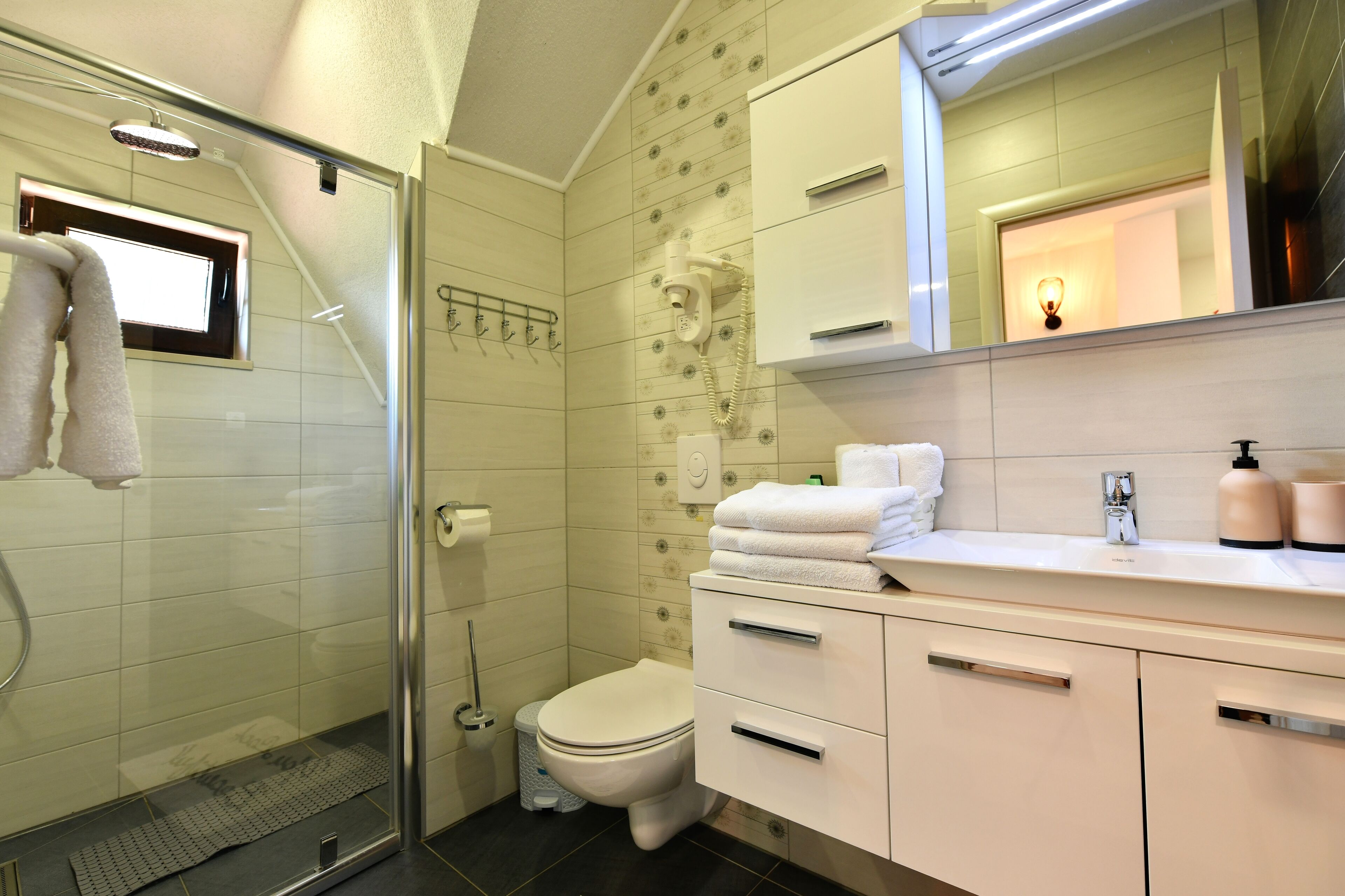 A modern bathroom with a glass shower enclosure, a toilet, and a vanity with a mirror.