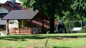 A traditional wooden building with a tiled roof, a stone chimney, and a swing set. - House Jelena (Rakovica)