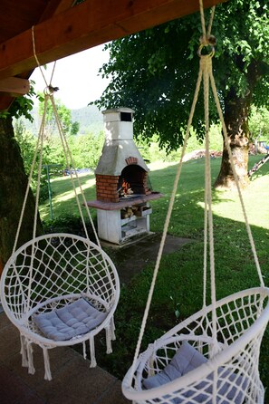Un área de estar rústica al aire libre con dos sillones blancos de mimbre y un horno de ladrillo.