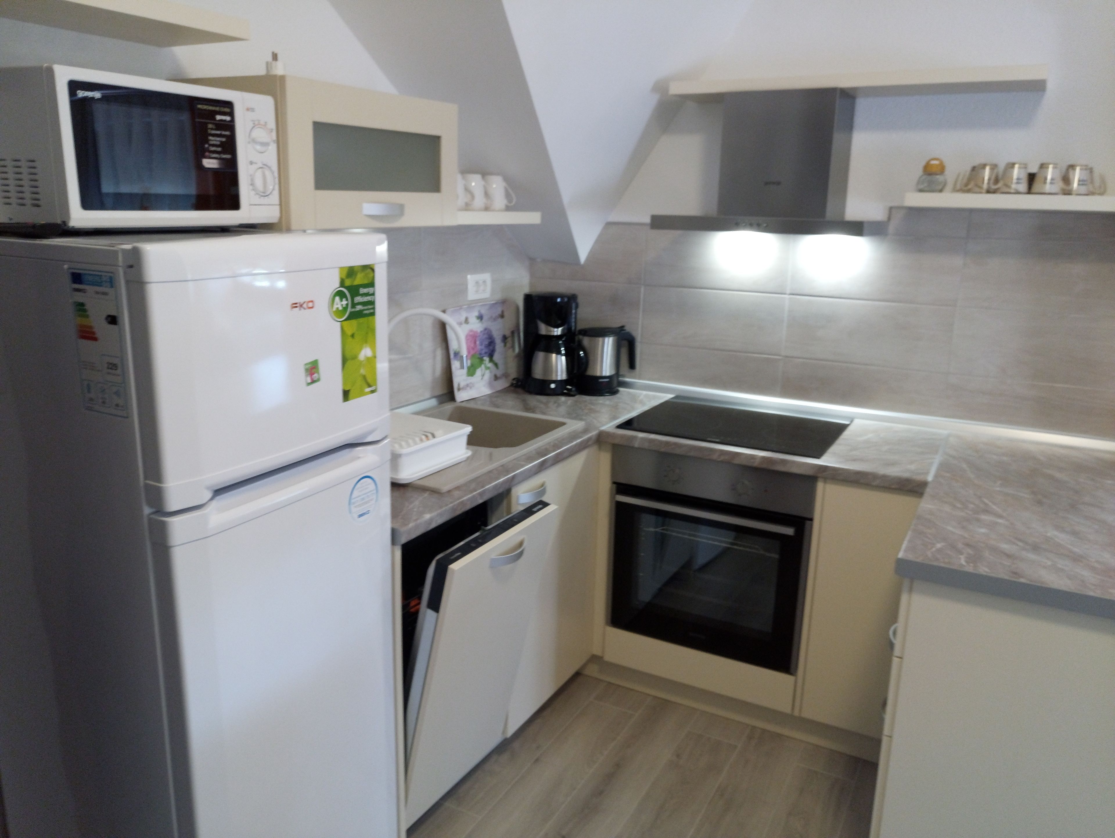 Cozinha compacta com geladeira, micro-ondas, forno e cafeteira.