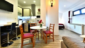 A modern kitchen with a dining area, a TV mounted on the wall, and a cozy living space with a sofa and a small table. - House Jelena (Rakovica)