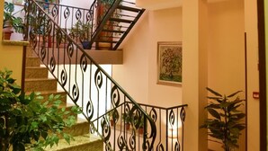 A staircase with a metal railing, carpeted steps, and a red carpet leading to a door. - Club Hotel Martin (Bansko)